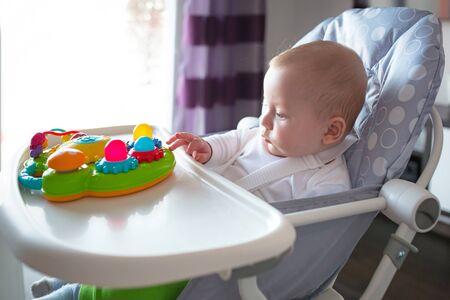 Baby boy sitting on the high chair for joyの写真素材