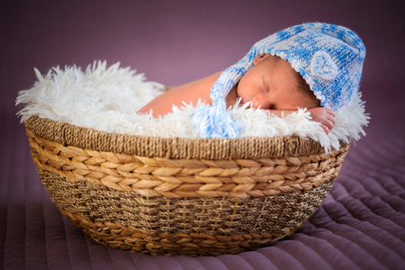 Newborn baby boy sleeping inside the wicker basketの写真素材