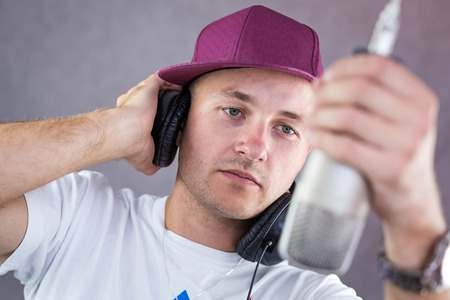 Man holding a headphone up his ear while holding onto a micの写真素材