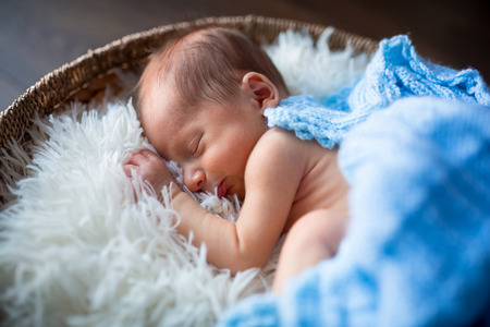Newborn baby boy sleeping inside the wicker basketの写真素材