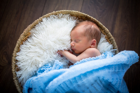 Newborn baby boy sleeping inside the wicker basketの写真素材