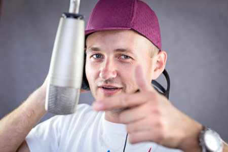 Man holding a headphone up his ear with hand gestureの写真素材