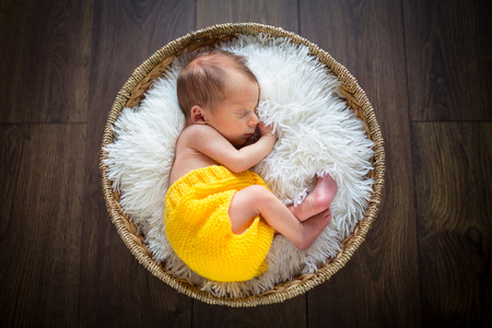 Newborn baby boy sleeping inside the wicker basketの写真素材