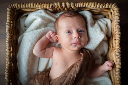Newborn baby boy lying down inside the wicker basketの写真素材
