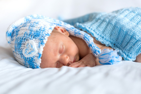 Newborn baby boy sleeping under blue blanketの写真素材