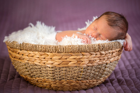 Newborn baby boy sleeping inside the wicker basketの写真素材
