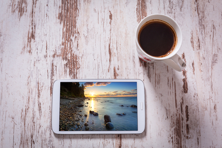 Tablet and black coffee on wooden table. Top view. Photo on screen coming from my gallery.の写真素材