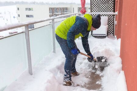 Man shoveling the show on the terrace after heavy snowfallの写真素材