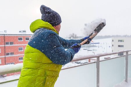 Man shoveling the show on the terrace after heavy snowfallの写真素材
