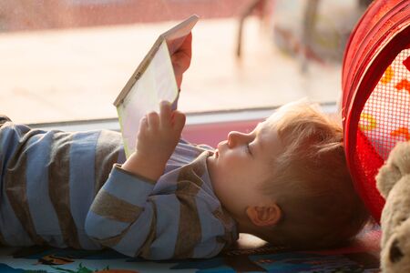 Little boy reading a book on the floorの写真素材