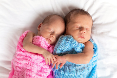 Newborn twins sleeping on bed togetherの写真素材