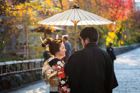 KYOTO, JAPAN - NOVEMBER 11, 2016: Japanese couple wearing traditional japanese kimonos walk on the street of Gion, Kyoto old town, Japan. Kimono is a Japanese traditional garment.のeditorial素材