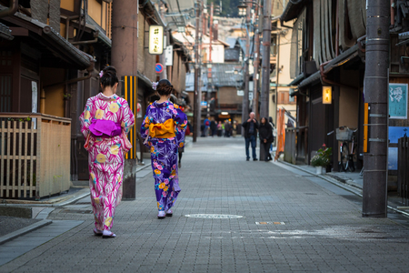 KYOTO, JAPAN - NOVEMBER 11, 2016: Young women wearing traditional japanese kimono walk on the street of Gion, Kyoto old town, Japan. Kimono is a Japanese traditional garment.のeditorial素材