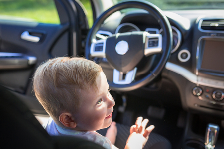 Happy boy sitting on the driver seat in the carの写真素材