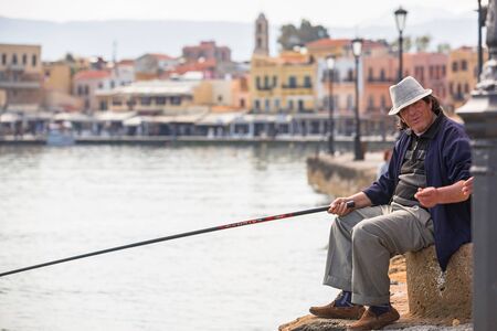 CHANIA, GREECE - APRIL 3, 2017 : Angler at the harbour of Chania on Crete, Greece. Chania is the second largest city of Crete and the capital of the Chania regional unit.のeditorial素材