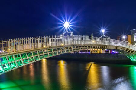 DUBLIN, IRELAND - FEBRUARY 20, 2012: The ha'penny bridge in Dublin at night, Ireland. Dublin is the capital and largest city of Ireland. Located on the east coast, at the mouth of the River Liffey.のeditorial素材