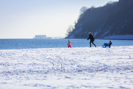 Mother with twins walking on snowy beach, Polandの写真素材