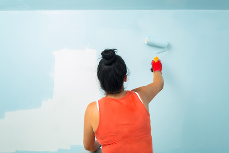 Woman at painting a room with paint rollerの写真素材