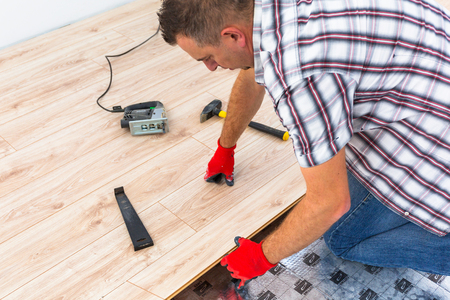 Handyman installing new laminated wooden floorの写真素材