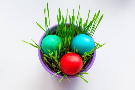 Painted Easter eggs in a bowl with grassの写真素材