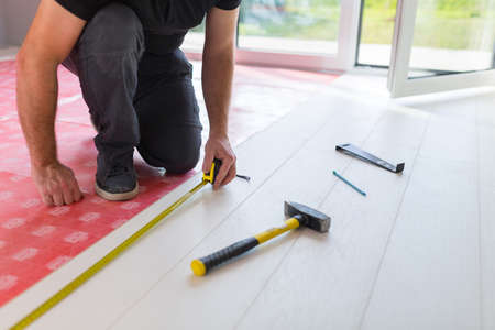 Handyman installing new laminated wooden floorの写真素材