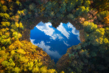 Aerial view of heart shaped pond in autumnal forestの写真素材