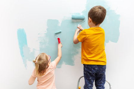 Kids are painting the walls of their room with a roller in turquoise color.の写真素材