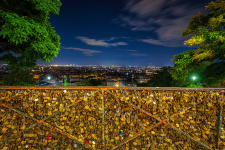 Paris, France - September 16, 2022: Pad locks with initials of people in love on Montmartre hill at night. Montmartre is a historic district of Paris, the capital of France.のeditorial素材