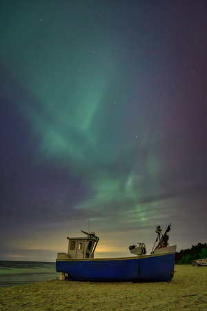 Aurora over the Baltic Sea on the beach in Katy Rybackie with fishing boat in Poland.の写真素材