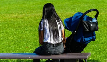 Young mother taking care of her baby son in a park. Baby sitter in the park.