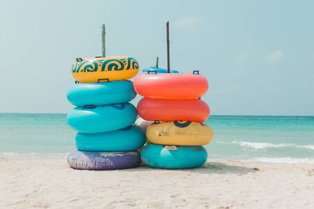 Colorful rubber ring on white sand beach, blue sea