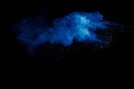 Blue powder explode cloud on black background.Launched blue dust particles splash on background.の写真素材