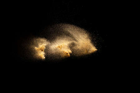 Golden sand explosion isolated on black background. Abstract sand cloud. Golden colored sand splash...