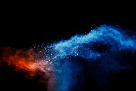 Blue orange color powder explosion on black background.の写真素材