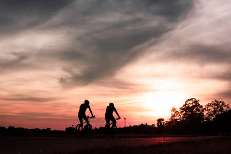 The couple of cyclist riding the road bike at sunset,silhouette image.の写真素材