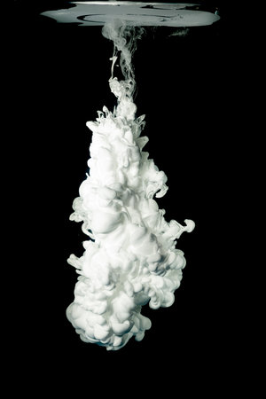 White ink in water, isolated on black background. Acrylic paint splash.の写真素材