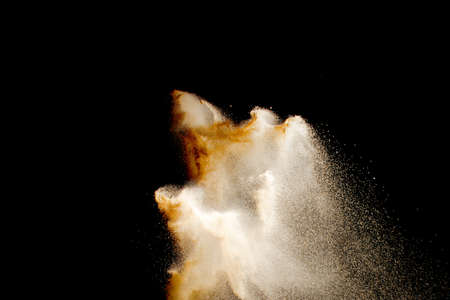 Brown color sand splash against black background.