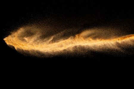 Brown colored sand splash.Dry river sand explosion isolated on black background.