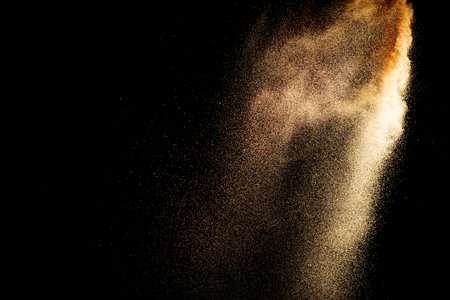 Sand flying explosion isolated on black backgroundの写真素材