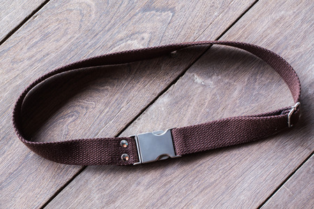 Dark brown canvas belt on wood background