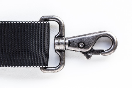 Black belt rope strap lanyard, hanging metal clasp snap latch hook carabiner, isolated macro closeup latchの写真素材