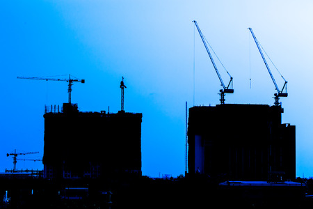 Industrial construction cranes and building silhouettesの写真素材