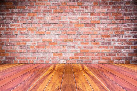 Grungy textured red brick and stone wall with warm brown wooden floor inside old neglected and deserted interior masonry and carpentry brickwork conceptの写真素材