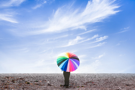 lonely woman holding umbrella standing on dry ground with blue sky cloudy. umbrella standing on dry groundの写真素材