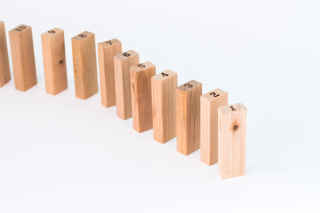 Hand and falling wood pieces dominoes on white backgroundの写真素材