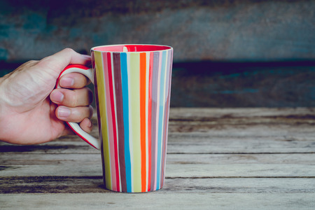 vintage soft tone with hand hold colorful mug.の写真素材