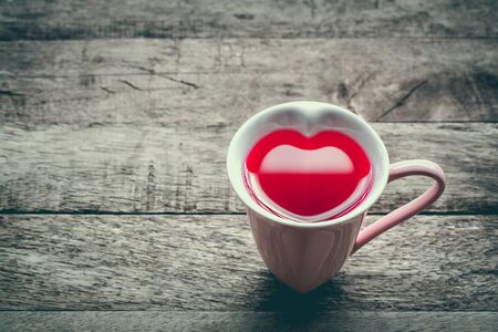 vintage soft color tone with glass heart red nectar on wooden backgroundの写真素材