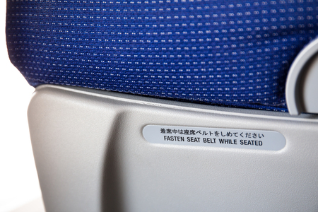 Fasten seat belt sign on the back of a seat from airliner.の写真素材