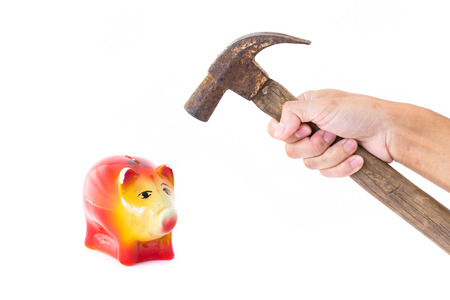 Man hand holding a hammer will knock into Pig piggy bank saving. The concept of financial assets, reliability deposits, insurance savings.の写真素材