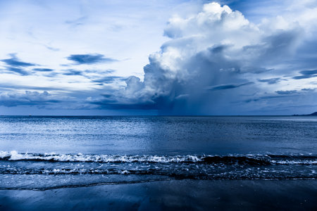 Summer day. Before Sunset streams through the clouds with waves blow to the beach.の写真素材